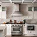ZLINE Designer Series Wall Mount Range Hood in Fingerprint Resistant Stainless Steel with Mirror Accents (655MR) in a luxury compact kitchen with matching range and microwave, front.